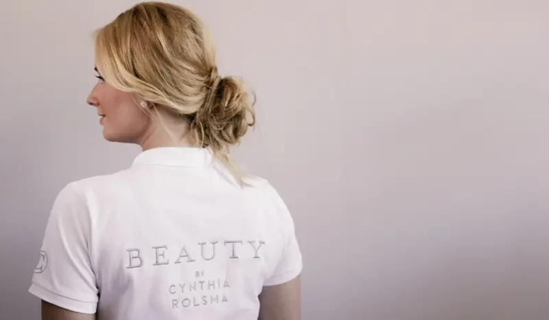 Cynthia Rolsma op de rug gezien, in haar witte shirt met het borduursel Beauty by Cynthia Rolsma